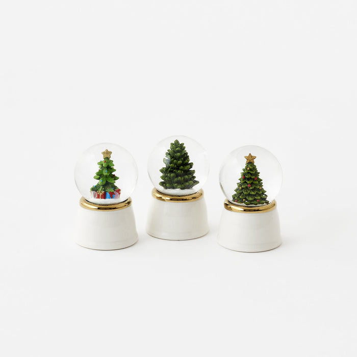 Three small snow globes with Christmas trees on a white background